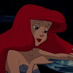 ariel from the little mermaid with red hair and blue eyes looking at something in her hand