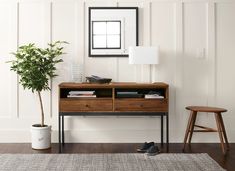 a living room with a wooden table and two stools next to a potted plant