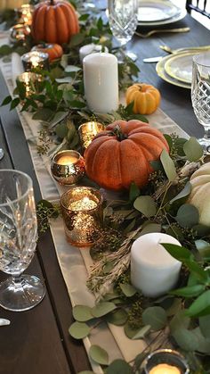 the table is set with candles, pumpkins and greenery for an elegant thanksgiving dinner