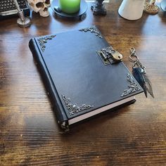 a black book sitting on top of a wooden table next to a candle and other items