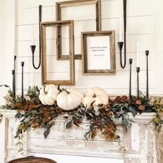 a mantel decorated with white pumpkins and greenery