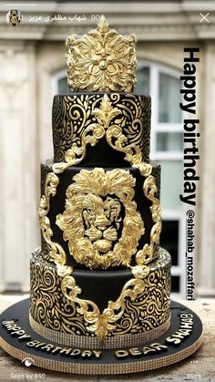 a three tiered black and gold wedding cake with a lion head on the top