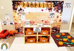 a display with pumpkins and other items on the floor in front of a bulletin board