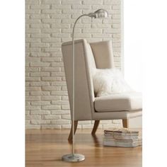 a white chair sitting in front of a brick wall with a lamp on top of it