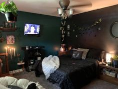 a bed room with a neatly made bed next to a tv on the wall and two candles in front of it