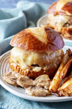 two sandwiches with meat and cheese are on a plate next to some french fries in front of them