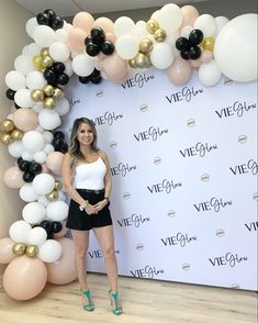 a woman standing in front of a backdrop with balloons