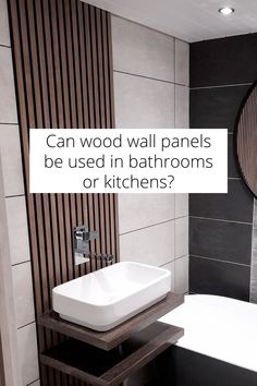 a white sink sitting next to a bathtub in a bathroom under a mirror with the words can wood wall panels be used in bathrooms or kitchens?