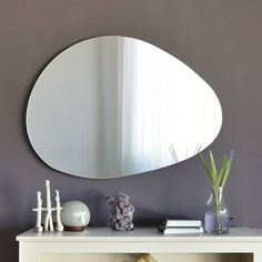 a white table topped with a mirror and vase