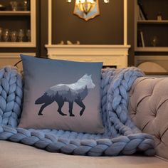 a pillow with a wolf on it sitting on a couch next to a blue blanket