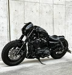 a black motorcycle parked in front of a concrete wall