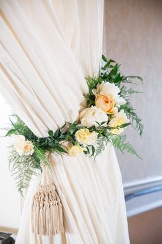 flowers and greenery are arranged on the drapes