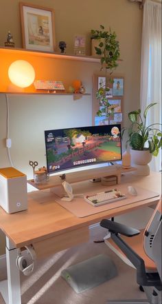 a desk with a computer on it in front of a window and potted plants