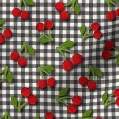 a checkered table cloth with cherries and leaves on black and white gingham