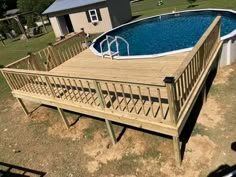 an above ground swimming pool with wooden decking and railing around the perimeter, surrounded by a fenced in yard