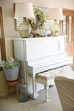 a living room with a white piano and two lamps