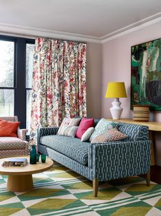 a living room filled with furniture next to a window covered in colorful pillows and curtains