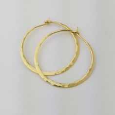 "Gorgeous Hammered Solid 18k Hoops made from 16 gauge (1.3mm) wire. 1.25\" Size photographed; 2\" size in 14k yellow gold shown in video METAL: Solid 18k Yellow Gold WIRE GAUGE/DIAMETER: 16 gauge (1.3mm) wire - Currently the thickest wire I offer EAR WIRE THICKNESS: Due to the thickness of the wire, the ear wire portion of the hoops will be tapered to approximately 18g, which is slightly thicker than standard ear wire thickness HAMMERED EFFECT: Each earring is made as a mirrored pair and the tex Hand Forged Earrings For Anniversary, Elegant Gold Hoop Earrings In Recycled Gold, Hammered 14k Yellow Gold Jewelry, 14k Yellow Gold Hammered Jewelry, Hammered Gold Plated Hoop Jewelry, Hammered 14k Gold-filled Hoop Earrings, Hammered Gold-plated Hoop Jewelry, Hammered Gold Sterling Silver Hoop Earrings, Elegant Hammered Hoop Earrings In Recycled Gold