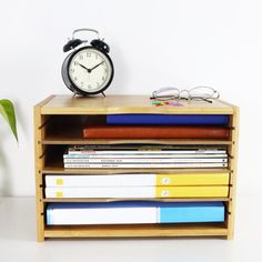 an alarm clock sitting on top of a wooden shelf filled with books and folders