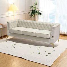 a white couch sitting on top of a hard wood floor next to a table and lamp