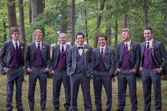 a group of men standing next to each other in front of some trees and grass