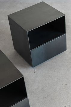 three black boxes sitting on top of a cement floor