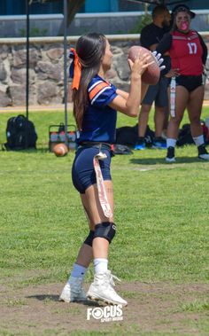 a woman holding a football on top of a field