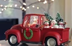 an old red truck with christmas decorations in the back