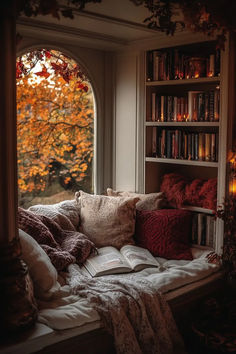 an open book on a window sill in front of a tree filled with leaves