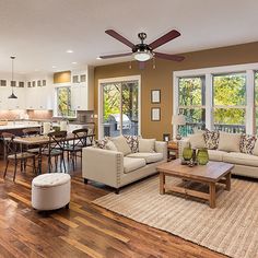 a living room filled with furniture next to a kitchen and an open concept dining area