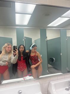 three women in bathing suits are taking a selfie in front of a bathroom mirror