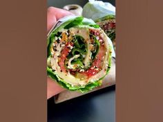 a hand holding a wrap filled with lettuce and toppings