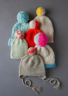 several knitted hats with pom poms on them