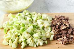 chopped up apples on a cutting board next to a bowl of whipped cream and chocolate chunks