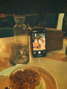 there is a cake on the table with a cell phone next to it and a vase