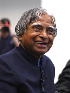 an old man with grey hair and blue shirt smiling