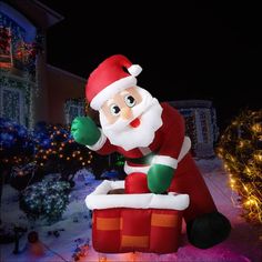 a large inflatable santa clause sitting on top of a christmas present box outside