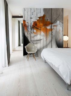 a white bed sitting next to a wall with a painting on it's side