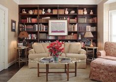 a living room filled with lots of furniture and bookshelves covered in shelves full of books