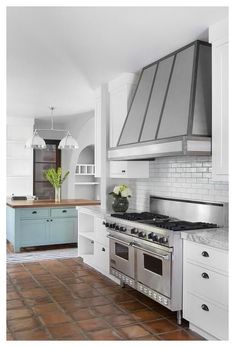 a kitchen with an oven, stove and counter tops in the middle of it's tile flooring