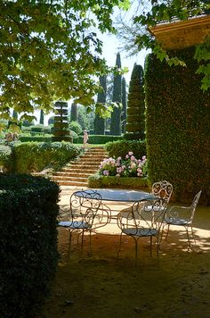 an outdoor table and chairs in the middle of a garden with steps leading up to it