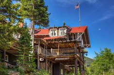 a wooden house with a flag on the top of it and trees in front of it