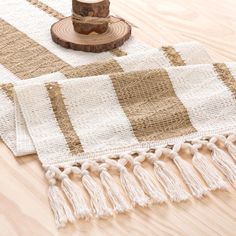 a table topped with a wooden slice of wood next to a white and brown rug