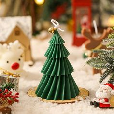 a small christmas tree sitting on top of a snow covered ground next to other ornaments