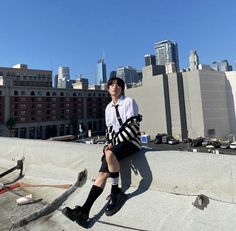 a man sitting on top of a cement wall next to a cityscape with tall buildings in the background