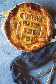 a pie with the words curry with the pot written on it next to a fork and spoon