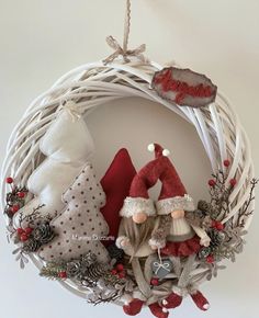 a christmas wreath with two gnomes hanging from it