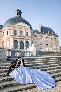 a bride and groom sitting on some steps in front of a large building with stairs leading up to it