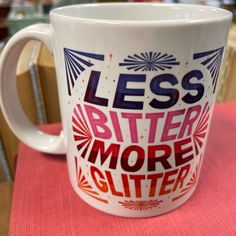 a coffee mug that says less butter more glitter on it sitting on a pink table cloth