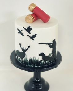 a white cake with black silhouettes and birds on it, topped with a red candle